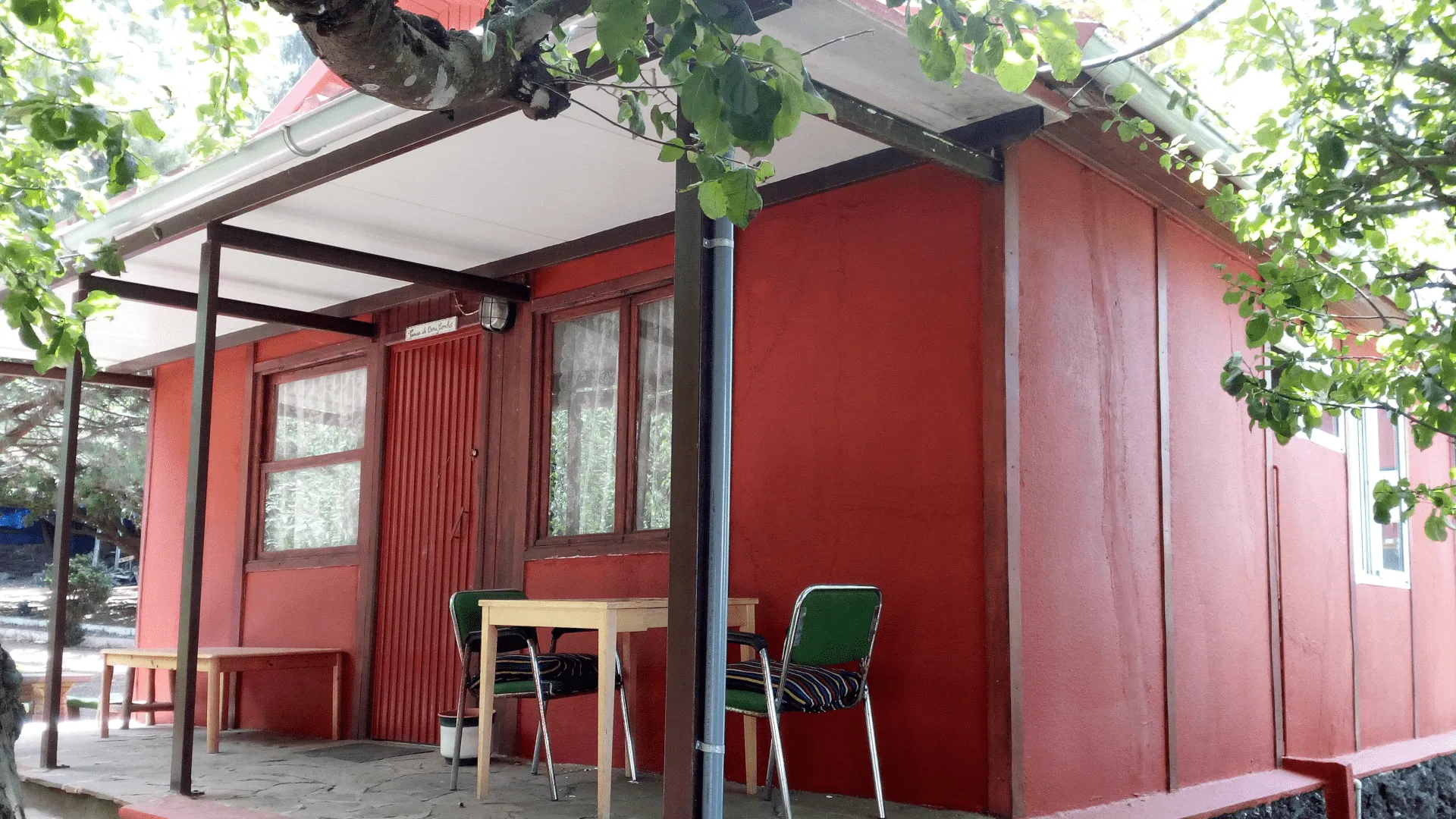 Casa roja con porche entre los árboles